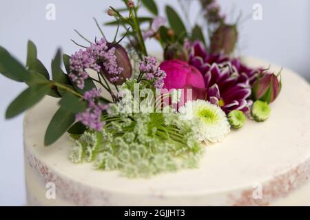 Hochzeitsträume - A close-up of a rustic wedding cake adorned with delicate flowers and greenery, showcasing a simple yet elegant design. Stock Photo