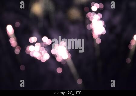 Purple light bokeh created by fireworks against dark sky Stock Photo