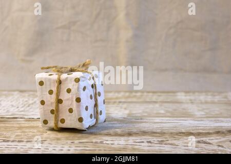 Gift box packed in kraft paper and tied with a twine, ecological packaging, recycled paper, zero waste, close up front view Stock Photo