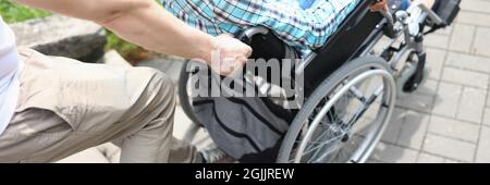 Man lifts a woman in wheelchair up stairs Stock Photo