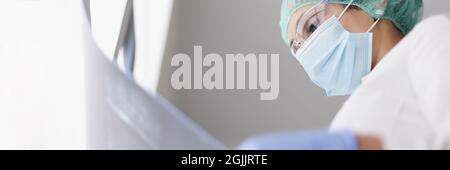 Doctor wearing protective mask and gloves examines an X-ray image Stock Photo
