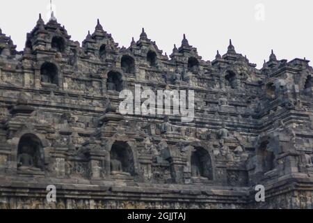 Detail of exterior wall of ancient Borobudur temple with meditating Buddha statues. No people. Popular tourist and Buddhist pilgrimage destination. Stock Photo