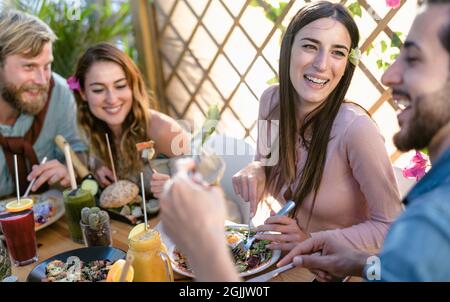 Happy young friends eating healthy lunch and drinking fresh smoothies in cafe brunch restaurant - Health nutrition lifestyle concept Stock Photo
