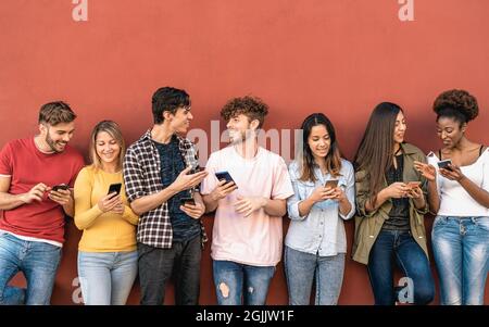 Young friends using mobile smartphone outdoor - Millennial generation having fun with new trends social media apps Stock Photo