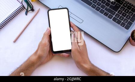 Mockup image of man hand using blank white desktop screen mobile phone on office desk. Stock Photo