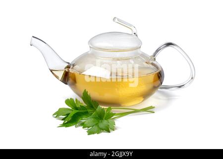 Glass teapot with lovage tea and a fresh twig of lovage in front isolated on white background Stock Photo