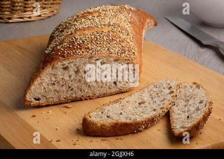 Sliced traditional sourdough loaf of bread in a special shape with seeds on a cutting board Stock Photo