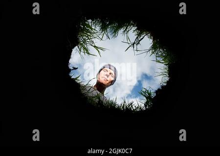 man looking into a deep hole Stock Photo