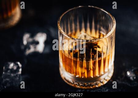 Whiskey with ice on a dark table against the background of bar bottles Stock Photo
