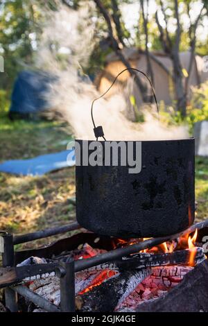 Camping kettle over burning campfire Stock Photo - Alamy