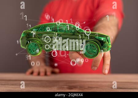 Shot of a human hand reaching for a green digital concept of a modern car with bits flying around it Stock Photo