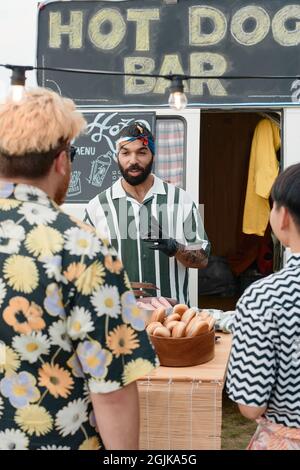 Young man selling fast food to people outdoors on the beach Stock Photo