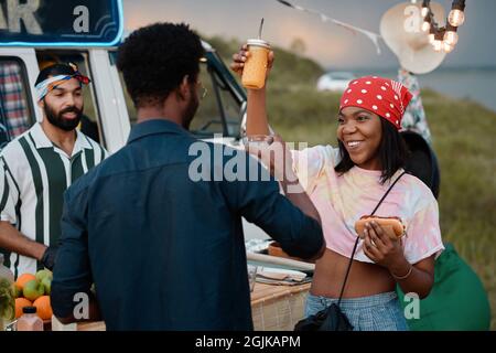 African happy couple eating fast food and dancing during party outdoors Stock Photo