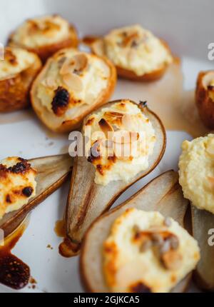 Baked pears stuffed with cottage cheese and sliced almonds nuts just made fresh sweet dessert still life photo. Healthy food and low calories meal con Stock Photo
