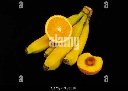Closeup shot of freshly sliced orange, peach, and bananas isolated on a dark background Stock Photo