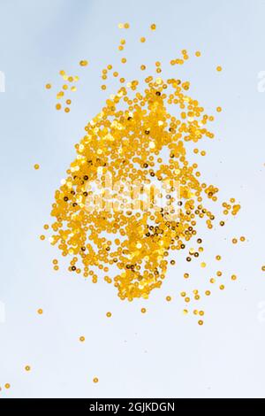 Light blue background with golden confetti, selective focus Stock Photo