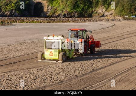 Cleaning Looe town beach early on a sunny morning. Cornwall UK Stock Photo