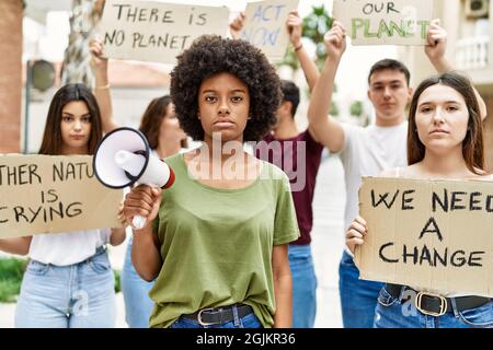 Group of young friends protesting and giving slogans at the street thinking attitude and sober expression looking self confident Stock Photo