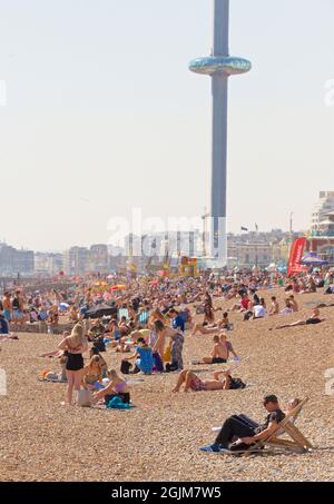 Crowded beaches of central Brighton and Hove. West of Brighton's Palace Pier. Summer holidays. Sussex, England, UK. i360 towering above. Stock Photo