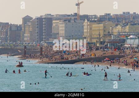 Crowded beaches of central Brighton and Hove. West of Brighton's Palace Pier. Summer holidays. Sussex, England, UK. Paddleboarders Stock Photo