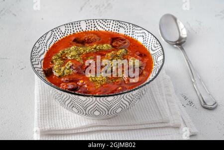 Bowl of kidney bean and chorizo stew garnished with pesto Stock Photo