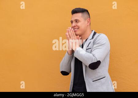 Latin man clasping his hands together and waiting anxiously for something.  Stock Photo