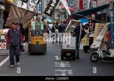 Shops, shoppers, tourists and electric carts in the streets of Tsukiji outer market. Tsukiji, Tokyo, Japan. Stock Photo