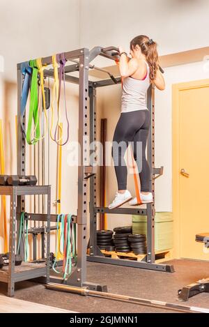 Athlete woman doing pull ups exercise with bar in gym Stock Photo