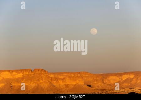 The Jabal Tuwaiq escarpment in Dhurma near Riyadh at sunset with full moon rising, Saudi Arabia Stock Photo