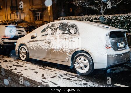 Covered with snow car silver Toyota Yaris hybrid electric car on the French street in central Strasbourg Stock Photo