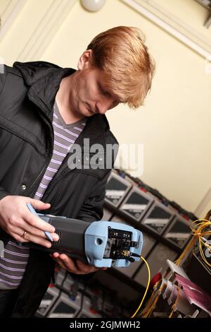 The technician looking at a reflectometer in a telecom site Stock Photo
