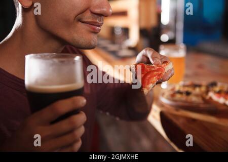 Cropped close up of a man smiling, enjoying beer and pizza at the bar Stock Photo