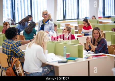 Female professor in a conversation with students at a lecture in a classroom Stock Photo