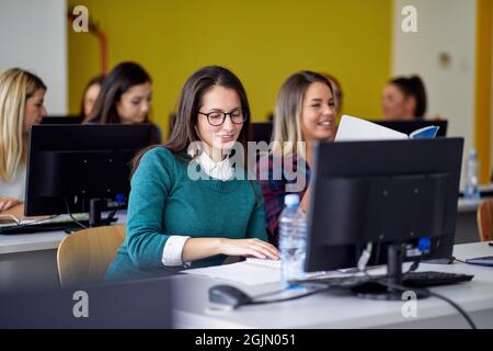 Students in front of computers at the informatics lecture in the university computer classroom. Smart young people study at the college. Education, co Stock Photo