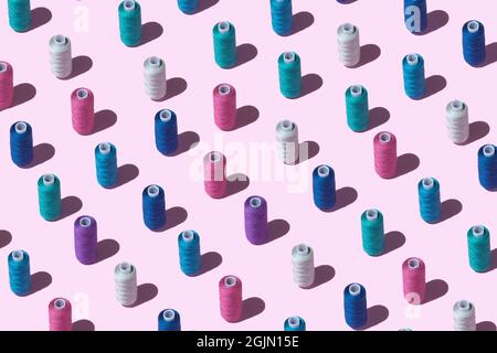 Pattern from spools of threads of different colors on a pink background. Spools of thread with shadow. Stock Photo