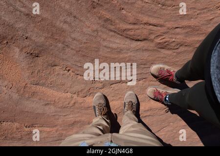 WHITE POCKET, UNITED STATES - Aug 16, 2021: A top view of feet on the red structures of rock Stock Photo