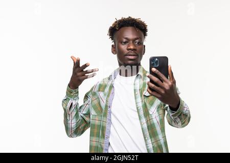 Portrait of happy smiling african-american guy talking with friends via video call, holding smartphone and waving hand in hello gesture, standing whit Stock Photo