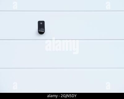 Detail of a white garage door with a black handle and lock on a clean minimalist surface. Stock Photo