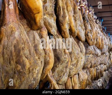 Dried pork thighs hang on the meat market. Spanish national dish of ham or jamon in a grocery. Iberian pork shopping in supermarket Spain. Dry and cur Stock Photo