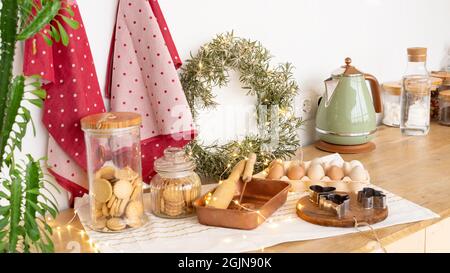 Festively decorated table with cookies and wreath for Christmas. Cookie cutters, cooking ingredients and utensils for gingerbread cookie bakery. Chris Stock Photo