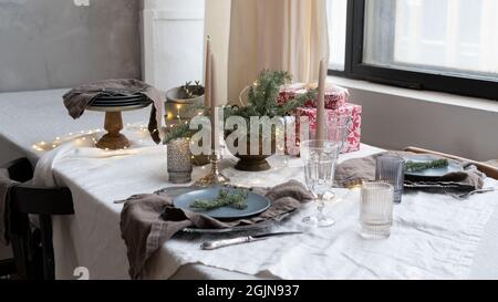 Christmas table setting. Linen tablecloth and napkins on the table. Christmas decor in the interior of the restaurant. Minimalistic rustic style in th Stock Photo