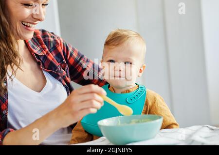 mother feeding baby food child eating family care childhood cute spoon Stock Photo