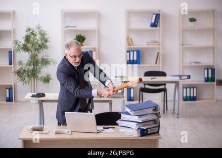 Old businessman employee unhappy with excessive work in the office Stock Photo