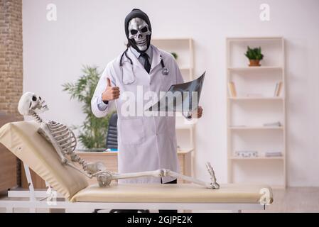 Devil doctor radiologist examining skeleton patient at the hospital Stock Photo