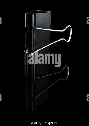 Metal stationery clip, Binder, black, on a black background, with reflection Stock Photo