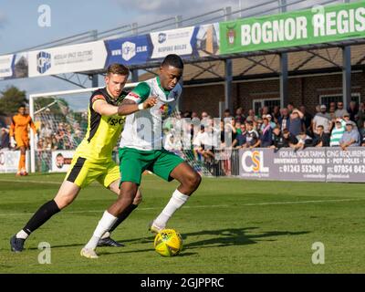 Bognor Regis, United Kingdom, 11th Sep 2021. Action from Isthmian Premier League (Southern) football (soccer) featuring the 'Rocks' (Bognor Regis Town FC versus Carshalton). Two ethnically diverse players tackle for the ball in front of a packed stand. Credit: Lyn Phillips/Alamy Live News Stock Photo