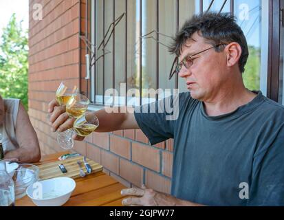 Mature man with glasses is holding three glasses with beer at the same time in one hand. Stock Photo