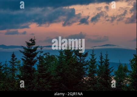 Sunset cloudscape over Rangeley Lake, ME, US. Stratocumulus castellanus clouds above a black spruce-balsam fir forest. Mountain ridges on the horizon. Stock Photo