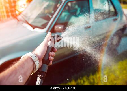 Hand holding water spray, washing car home concept Stock Photo