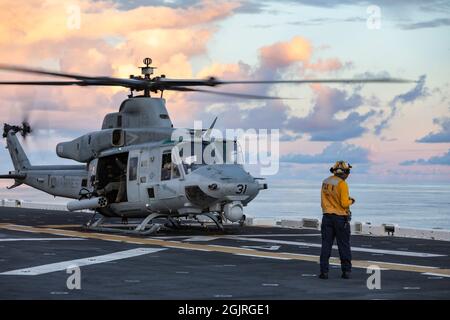 PACIFIC OCEAN (Aug. 21, 2021) A U.S. Sailor assigned to amphibious assault ship USS Essex (LHD 2), directs a UH-1Y Venom with Marine Medium Tiltrotor Squadron (VMM) 165 (Reinforced), 11th Marine Expeditionary Unit (MEU), before takeoff from Essex, Aug. 21. The Marines and Sailors of the 11th MEU are underway conducting routine operations as part of the Essex Amphibious Ready Group (MEU) in U.S. 3rd Fleet. (U.S. Marine Corps photo by Sgt. Seth Rosenberg) Stock Photo